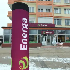 Duży, fioletowy słup z logo Energa przed budynkiem salonu sprzedaży.